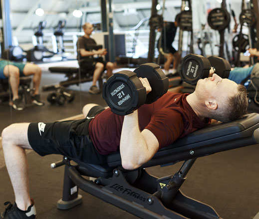 Image of a man doing the dumbbell press exercise in the gym