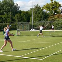 A doubles match on an outdoor tennis court. 
