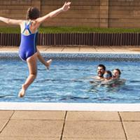 Child jumping into the pool with family